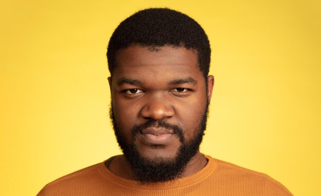 Portret młodego mężczyzny afro-amerykańskiego na żółtym tle, wyraz twarzy.