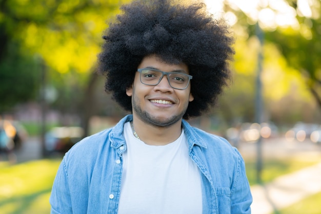 Portret młodego mężczyzny łacińskiego afro, uśmiechając się, stojąc na zewnątrz na ulicy