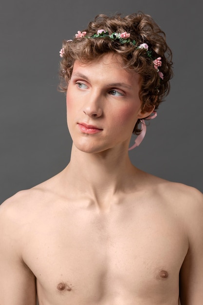 Bezpłatne zdjęcie portret młodego mężczyzny noszenia makijażu i wieniec kwiatowy