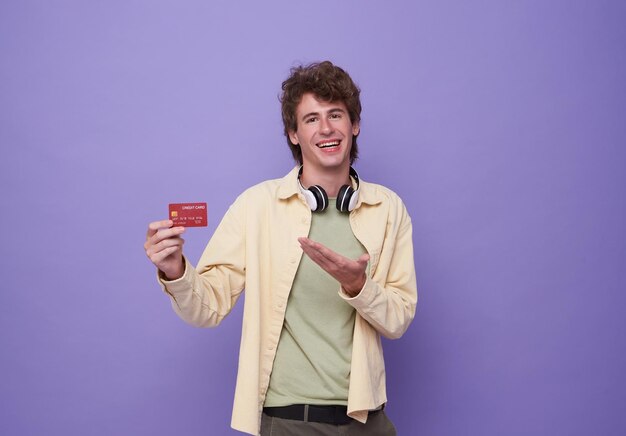 Portret młodego mężczyzny przedstawiającego kartę kredytową w ręku, pokazując zaufanie i pewność, że dokona płatności