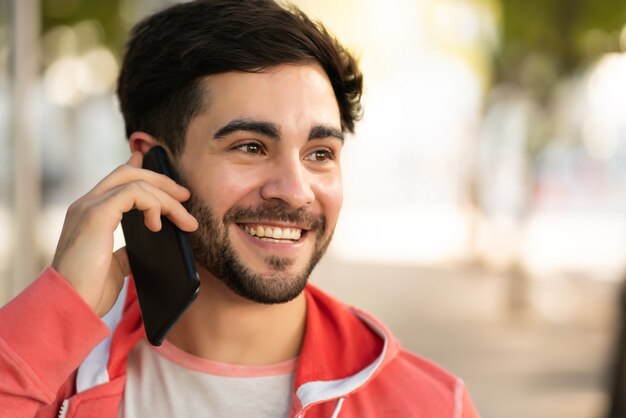 Portret młodego mężczyzny rozmawia przez telefon, stojąc na zewnątrz na ulicy. Koncepcja miejska.