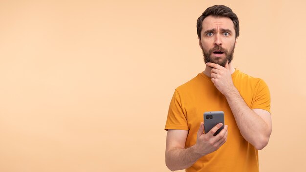 Portret młodego mężczyzny trzymającego smartfona i patrzącego na zaniepokojonego