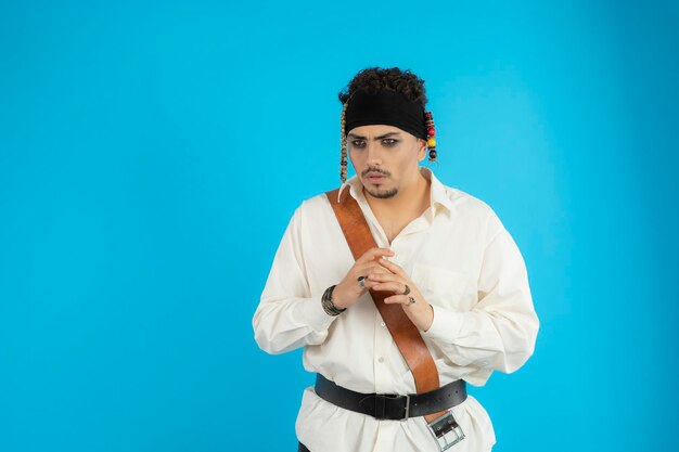 Portret młodego przystojnego pirata na niebieskim tle. Zdjęcie wysokiej jakości