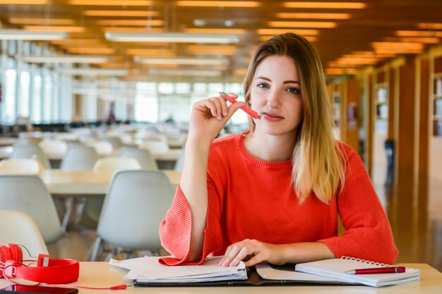 Portret młodego studenta studiującego w bibliotece uniwersyteckiej. Koncepcja edukacji i stylu życia.