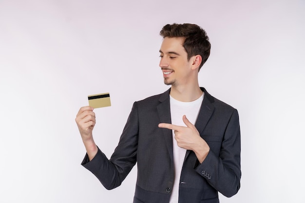 Bezpłatne zdjęcie portret młodego uśmiechniętego przystojnego biznesmena pokazującego kartę kredytową odizolowywającą nad białym tłem