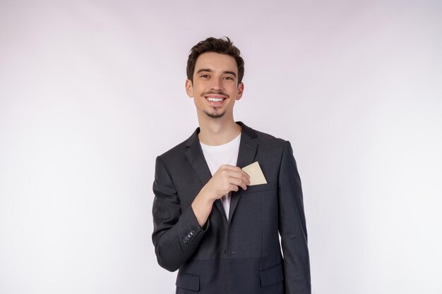 Portret młodego uśmiechniętego przystojnego biznesmena pokazującego kartę kredytową odizolowywającą nad białym tłem