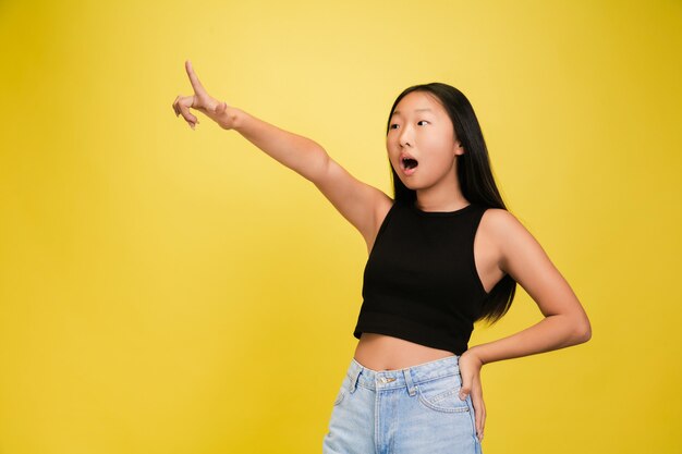 Portret młodej dziewczyny azjatyckiej odizolowanej na żółtej ścianie