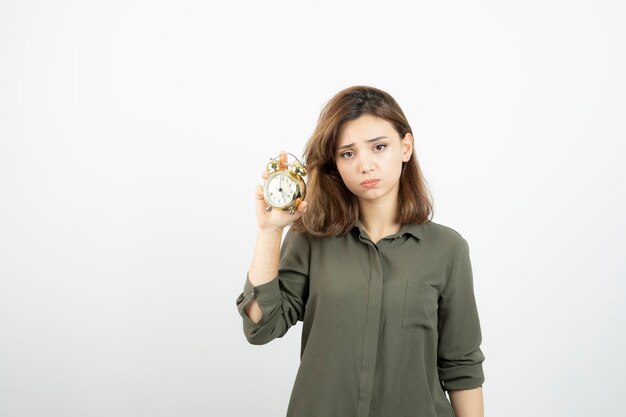 Portret młodej dziewczyny w stroju dorywczo trzyma budzik. Zdjęcie wysokiej jakości
