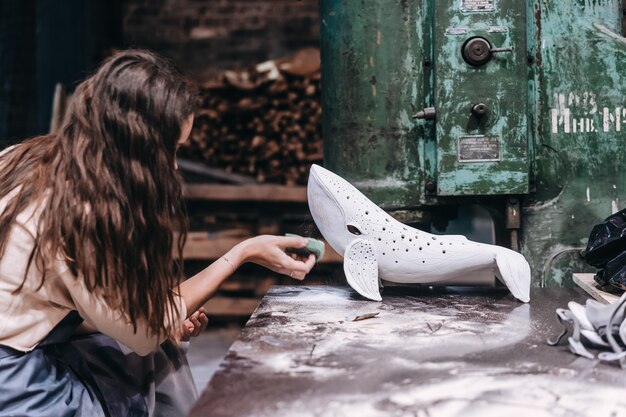 Portret młodej kobiety korzystających z ulubionej pracy w warsztacie. potter starannie pracuje nad ceramicznym wielorybem