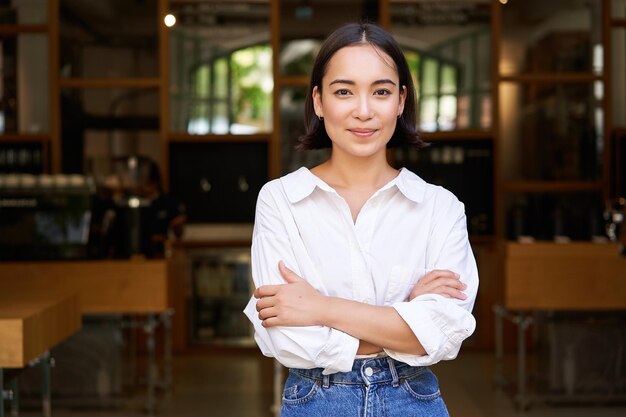 Portret młodej kobiety-przedsiębiorcy, azjatyckiego właściciela firmy lub menedżera, siedzącej pewnie uśmiechającej się do ok