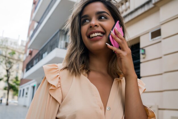 Portret młodej kobiety rozmawia przez telefon, stojąc na zewnątrz na ulicy