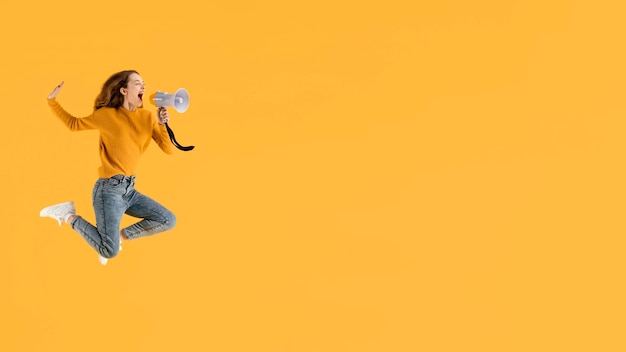 Bezpłatne zdjęcie portret młodej kobiety skaczącej z megafonem