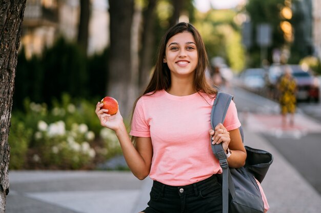 Portret młodej kobiety trzymającej jabłko na tle ulicy