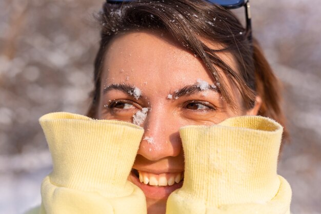 Portret młodej kobiety w zimowym lesie w słoneczny dzień ze śnieżnobiałym uśmiechem, wygłupiać się