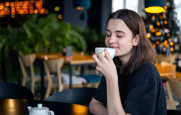 Bezpłatne zdjęcie portret młodej kobiety z filiżanką herbaty w kawiarni
