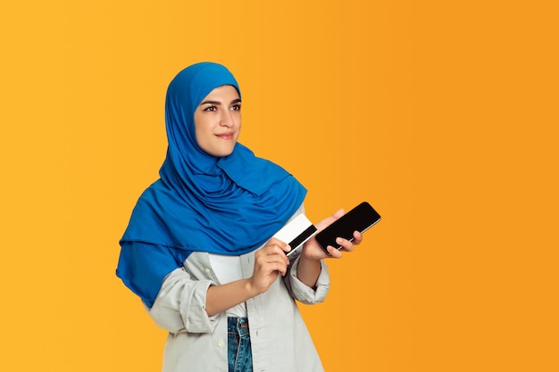 Portret młodej muzułmańskiej kobiety na żółtej ścianie