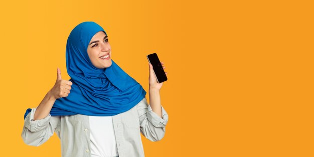 Portret młodej muzułmańskiej kobiety odizolowanej na żółto