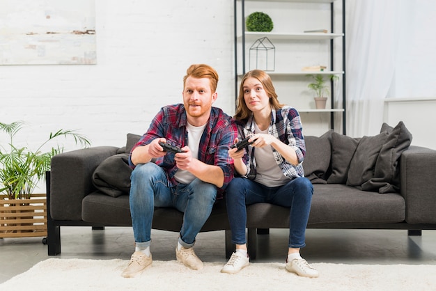 Bezpłatne zdjęcie portret młodej pary siedzi na kanapie, grając w gry wideo