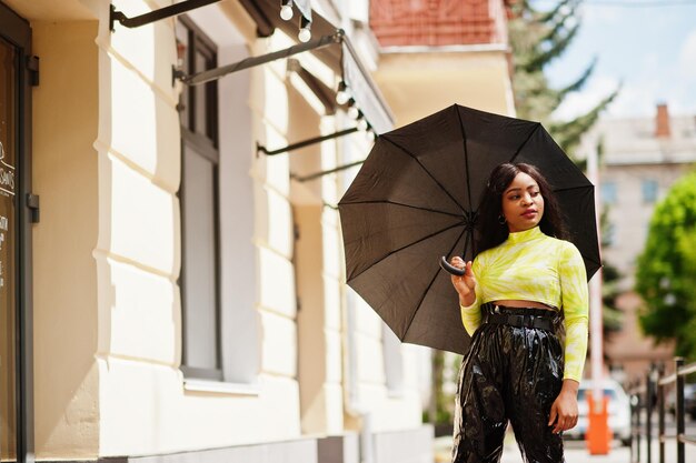 Portret młodej pięknej afroamerykańskiej kobiety trzymającej czarny parasol