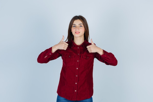 Portret młodej pięknej kobiety pokazując kciuk do góry w koszuli i wyglądający pewnie