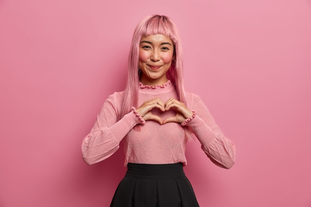 Portret Młodej Romantycznej Azjatki Kształtuje Gest Serca Kochankowi, Wysyła Uczucie I Miłość, Wyraża Współczucie, Nosi Długą Różową Perukę