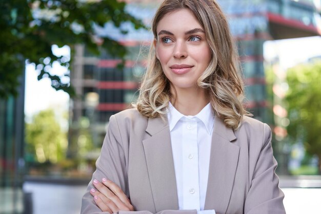 Portret młodej udanej bizneswoman w garniturze, skrzyżowane ramiona na klatce piersiowej, uśmiech i wygląd pewny siebie stan