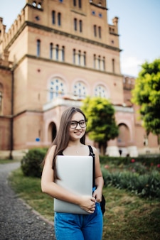 Portret młody azjatycki kobieta uczeń używa pastylkę lub laptop w mądrze i szczęśliwej pozie przy uniwersytetem lub szkołą wyższa