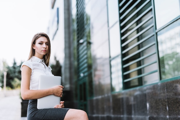 Portret młody bizneswomanu mienia laptop patrzeje kamerę