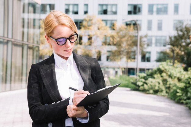 Portret młody bizneswomanu writing na schowku z piórem