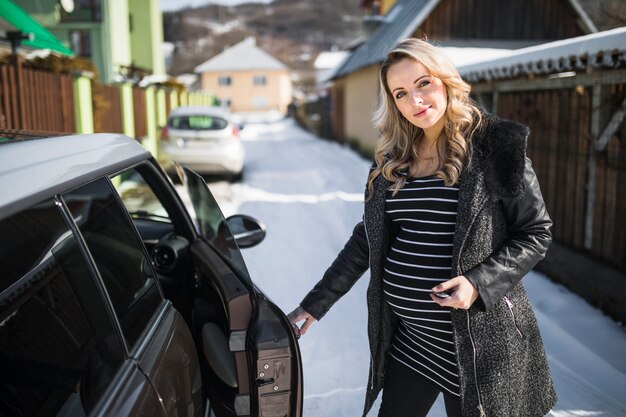 Portret młody kobieta w ciąży otwiera samochodowego drzwi