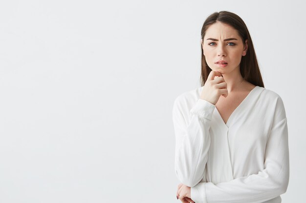 Portret młody piękny brunetka bizneswoman marzy myślący marszczący brwi. Dłoń na brodzie.