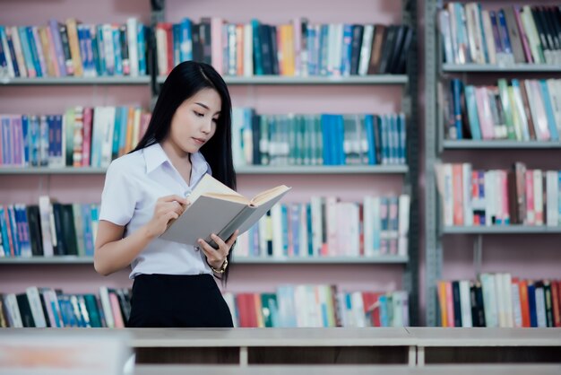 Portret młody uczeń czyta książkę w bibliotece