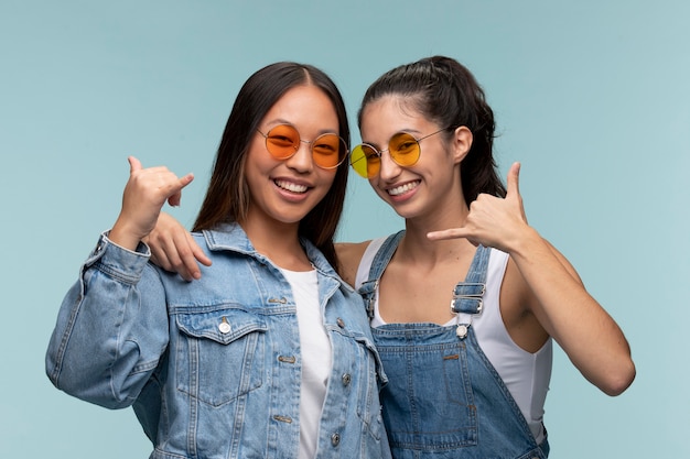 Portret młodych nastoletnich dziewcząt w okularach przeciwsłonecznych pokazujących znak wywoławczy