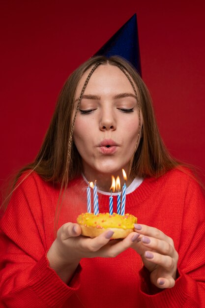 Portret nastolatka dmuchającego w urodzinowe świeczki w urodzinowym kapeluszu