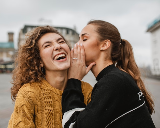 Portret nastolatka szepczącego do ucha przyjaciółki