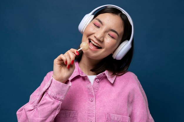 Portret nastolatki słuchającej muzyki i liżącej lizaka