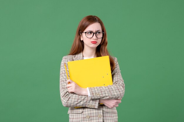 Portret nauczycielki trzymającej żółte pliki na zielono