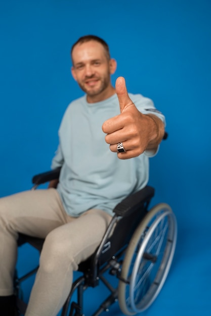 Portret niepełnosprawnego mężczyzny na wózku inwalidzkim, który daje aprobatom
