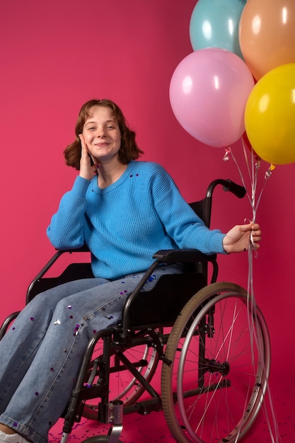 Portret niepełnosprawnej kobiety na wózku inwalidzkim z balonami
