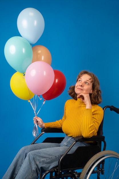 Portret niepełnosprawnej kobiety na wózku inwalidzkim z balonami