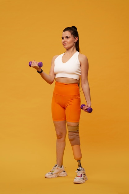 Portret niepełnosprawnej kobiety z protezą nogi ćwiczącej z ciężarami