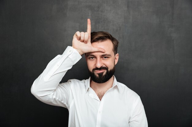 Portret nieszczęśliwego faceta 30s pozuje na kamerze i pokazuje nieudacznika znaka na jego czole nad grafitem