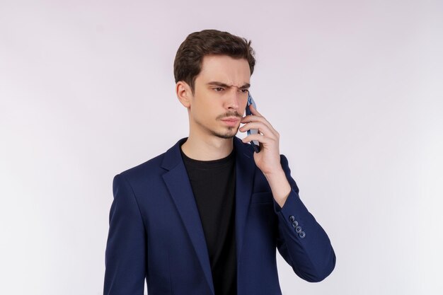Portret niezadowolony przystojny biznesmen rozmawia przez telefon komórkowy i stoi na białym tle nad białym tłem