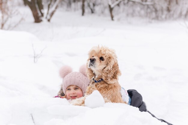 Portret odważnego psa w śniegu z dzieckiem płci żeńskiej na zewnątrz