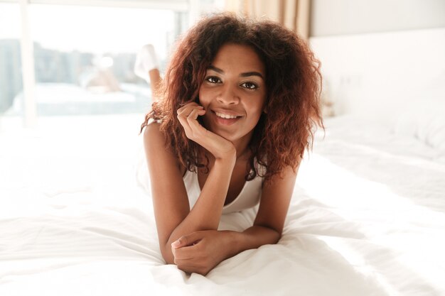Portret ono uśmiecha się i siedzi w łóżku afrykańska kobieta
