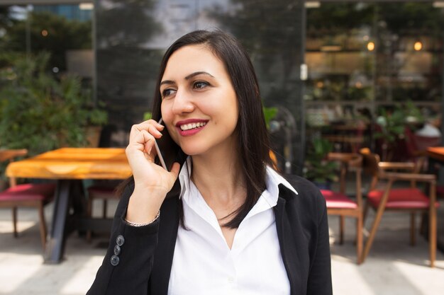 Portret opowiada na telefonie komórkowym w kawiarni młody bizneswoman