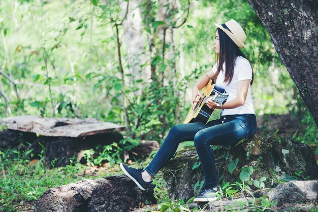 Portret piękna dziewczyna bawić się gitarę z writing przy naturą