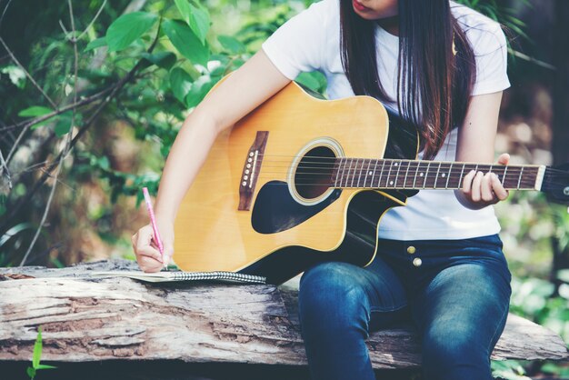 Portret piękna dziewczyna bawić się gitarę z writing przy naturą