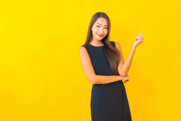 Portret piękna młoda azjatycka biznes kobieta uśmiech z akcją na żółtym tle koloru