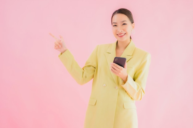 Portret piękna młoda azjatycka biznesowa kobieta używa inteligentnego telefonu komórkowego z filiżanką kawy na kolor